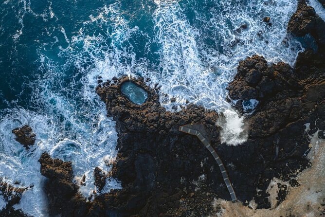 The Brimketill lava rock pool from above, Atlantic surf breaking over the black rock around it