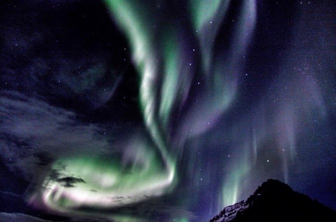 Green aurora over a dark lava field under a clear winter sky