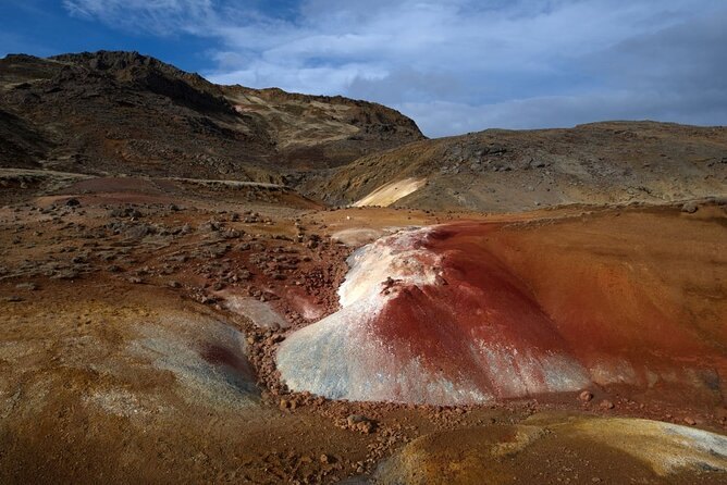 A rust-red cinder crater standing out of the brown lava plain on Reykjanes