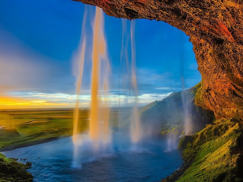 Seljalandsfoss photographed from the path behind the falling water at golden hour