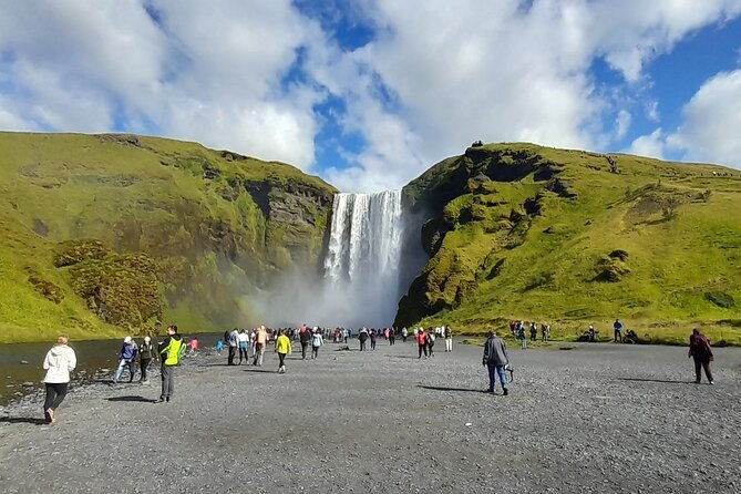 Skogafoss falling in a single sheet between green slopes on the south coast